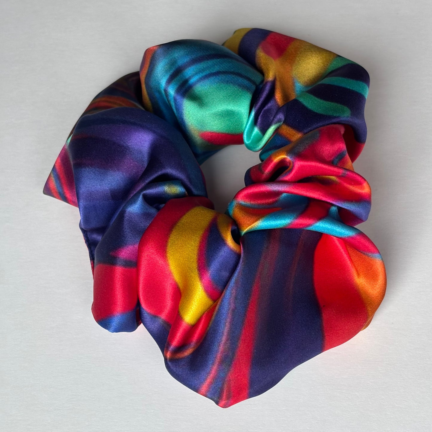 Curlora silk scrunchie in carnival multi colour print on marble surface