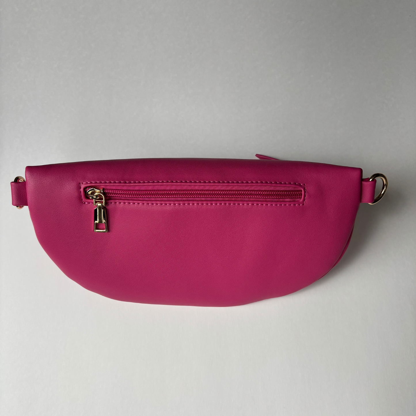 Rear view of Curlora sling bag in fuscia with storage pockets and gold zip detail 