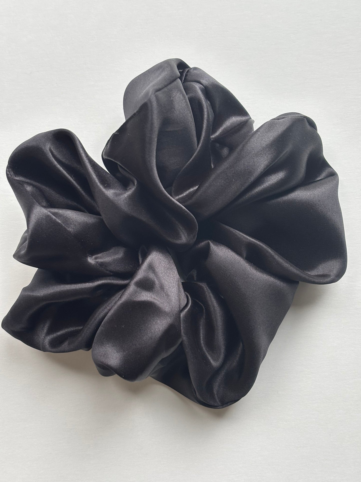 Curlora silk scrunchie for natural hair in black on marble surface