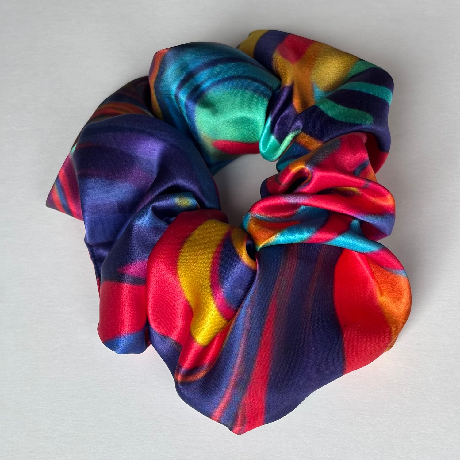 Curlora silk scrunchie in carnival multi colour print on marble surface